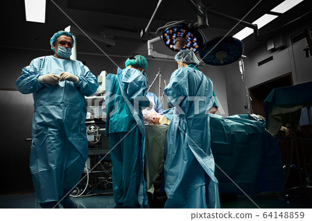 Surgical team operating on patient in theater in hospital Surgical team operating on patient in theater in hospital 64148859