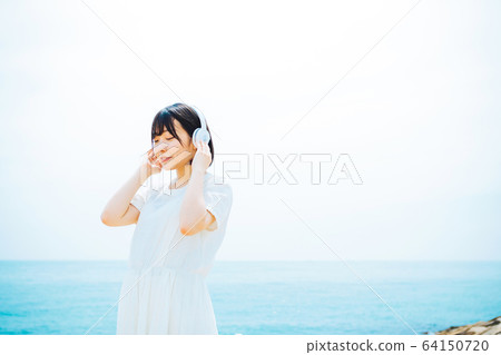 Woman listening to music at sea 64150720