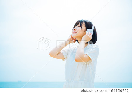 Woman listening to music at sea Woman listening to music at sea 64150722
