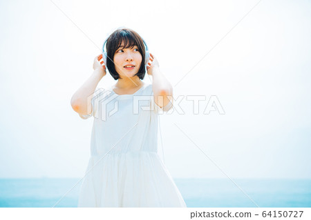 Woman listening to music at sea Woman listening to music at sea 64150727
