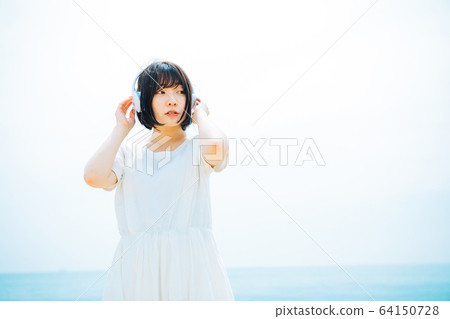Woman listening to music at sea Woman listening to music at sea 64150728