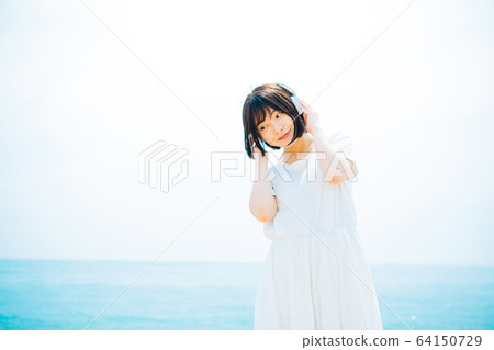 Woman listening to music at sea Woman listening to music at sea 64150729
