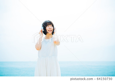 Woman listening to music at sea Woman listening to music at sea 64150730