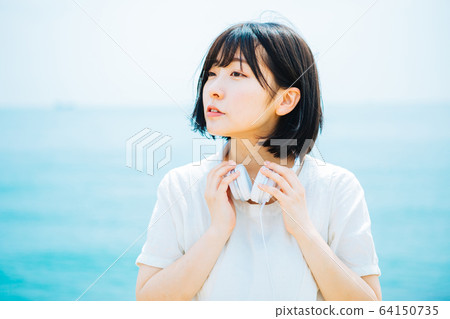 Woman listening to music at sea 64150735