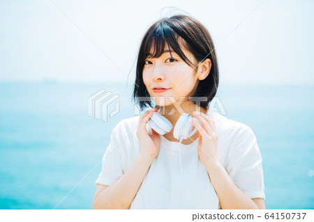Woman listening to music at sea 64150737