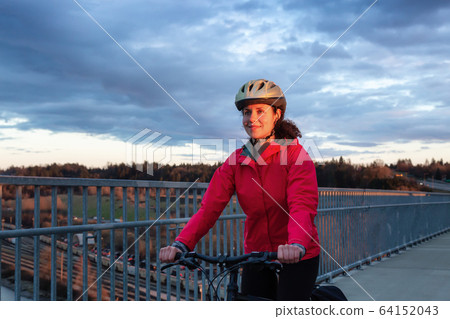 Caucasian Woman riding a Bicycle on a path at Port Mann Bridge 64152043