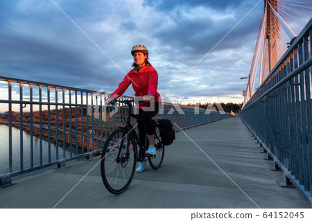 Caucasian Woman riding a Bicycle on a path at Port Mann Bridge 64152045
