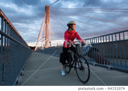 Caucasian Woman riding a Bicycle on a path at Port Mann Bridge 64152074