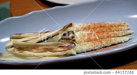 Delicious snack of fried, grilled or roasted baby corn on the table. Vegetarian cuisine Delicious snack of fried, grilled or roasted baby corn on the table. Vegetarian cuisine 64157288