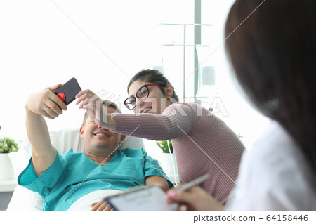 Husband and wife take selfie in hospital bed 64158446