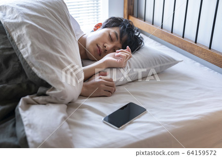 Young man sleeping with his smartphone in bed Young man sleeping with his smartphone in bed 64159572