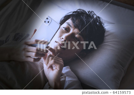 A man operating a smartphone while sleeping 64159573