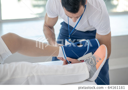 Nice young doctor holding a special bandage Nice young doctor holding a special bandage 64161181