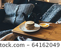Pancakes with honey on wooden tray in cozy room. 64162049