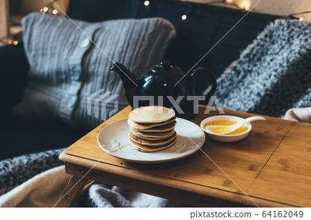 Pancakes with honey on wooden tray in cozy room. Pancakes with honey on wooden tray in cozy room. 64162049
