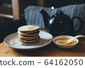 Pancakes with honey on wooden tray in cozy room. 64162050