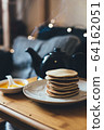 Pancakes with honey on wooden tray in cozy room. 64162051