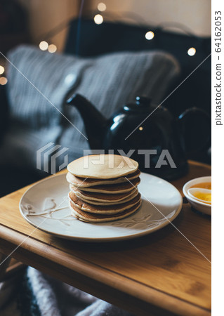 Pancakes with honey on wooden tray in cozy room. Pancakes with honey on wooden tray in cozy room. 64162053