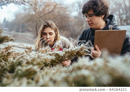 Scientists are studying plant species in the forest. 64164221
