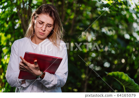 Young female agricultural engineer working in greenhouse. Young female agricultural engineer working in greenhouse. 64165079
