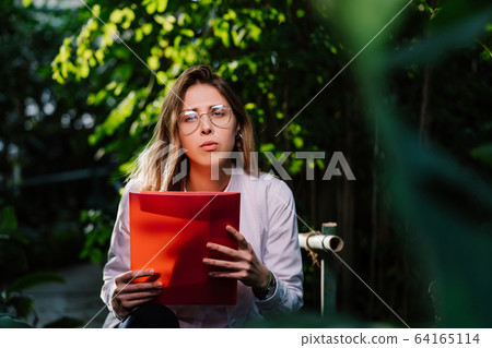 Young female agricultural engineer working in greenhouse. Young female agricultural engineer working in greenhouse. 64165114