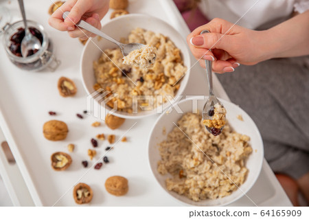 Happy mom and daughter have healthy breakfast in bed on a sunny morning. Oatmeal porridge with nuts Happy mom and daughter have healthy breakfast in bed on a sunny morning. Oatmeal porridge with nuts 64165909