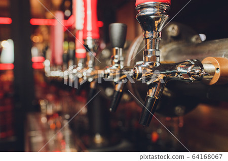 The bar counter with bottles and apparatus for dispensing beer. Apparatus for dispensing beer at the bar. Pub. The bar in the restaurant. Apparatus for dispensing beer in a restaurant. 64168067