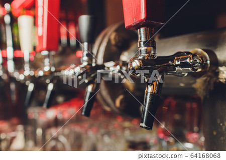 The bar counter with bottles and apparatus for dispensing beer. Apparatus for dispensing beer at the bar. Pub. The bar in the restaurant. Apparatus for dispensing beer in a restaurant. 64168068