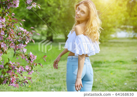 Beautiful young woman walking near the blossoming Beautiful young woman walking near the blossoming 64168630