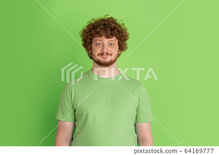 Caucasian young man's monochrome portrait on green studio background 64169777