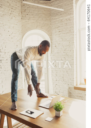 Young african-american man doing yoga at home while being quarantine and freelance working Young african-american man doing yoga at home while being quarantine and freelance working 64170641