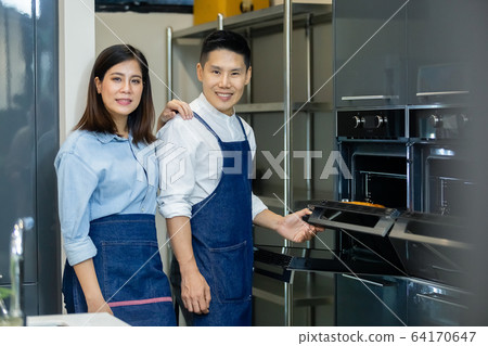 man and woman, happy asian couple standing with pastry oven making bakery in kichen. man and woman, happy asian couple standing with pastry oven making bakery in kichen. 64170647