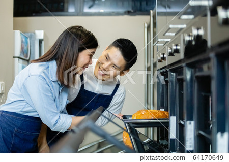 man and woman, happy asian couple standing with pastry oven making bakery in kichen. 64170649