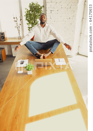 Young african-american man doing yoga at home while being quarantine and freelance working Young african-american man doing yoga at home while being quarantine and freelance working 64170653