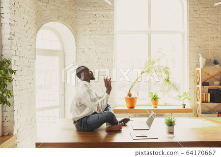 Young african-american man doing yoga at home while being quarantine and freelance working Young african-american man doing yoga at home while being quarantine and freelance working 64170667