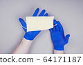 Man hands in blue disposal gloves hold disposal medicine face mask 64171187