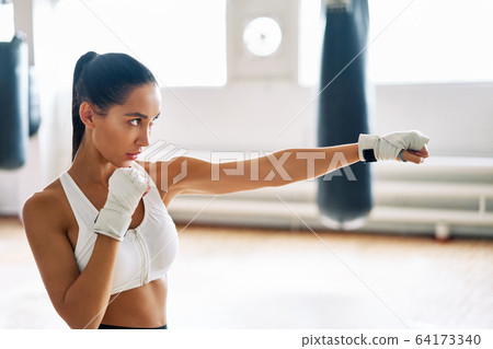 Female boxer practicing her punches at a boxing studio 64173340