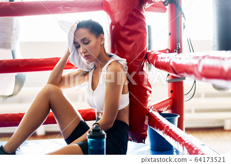 Young beautiful woman relax after fight or workout exercising in boxing ring Young beautiful woman relax after fight or workout exercising in boxing ring 64173521