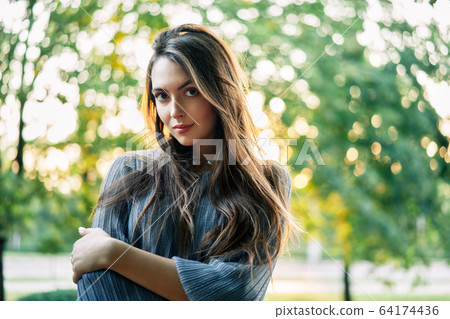 Young beautiful woman outdoors on green background summer nature 64174436