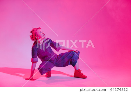 Young stylish girl dancing in the Studio on a colored neon background. Music dj poster design. Young stylish girl dancing in the Studio on a colored neon background. Music dj poster design. 64174812