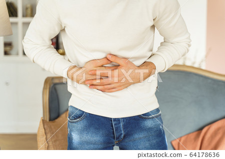 Young man suffering from an abdominal pain 64178636