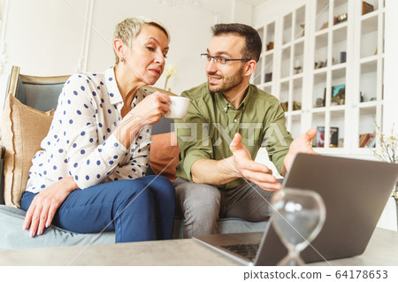 Pleased fortune-teller gazing at a serious lady 64178653