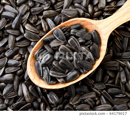 Sunflower seeds in a wooden spoon, background. The 64179017