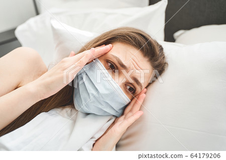 Girl with a splitting headache lying in bed Girl with a splitting headache lying in bed 64179206