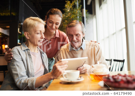 Family using tablet pc in cafe 64179490