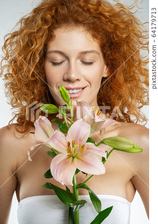 Happy beautiful red lady holding pink lilies Happy beautiful red lady holding pink lilies 64179713