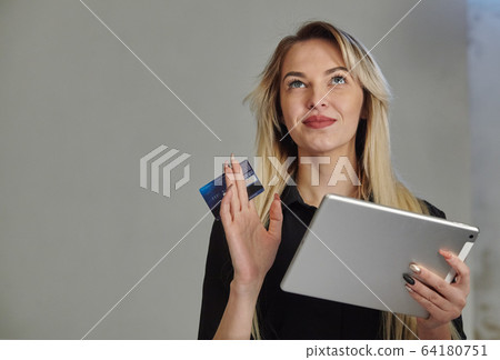 Young woman with credit card shopping online on digital tablet while lying at home Young woman with credit card shopping online on digital tablet while lying at home 64180751