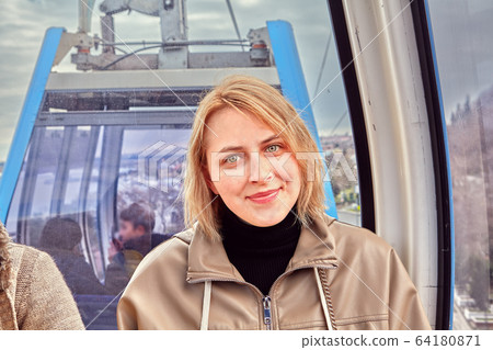 Young caucasian woman in cabin of cable car. 64180871
