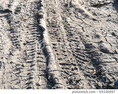 a wheel tracks on gray clay dirt road after rain. a wheel tracks on gray clay dirt road after rain. 64180997
