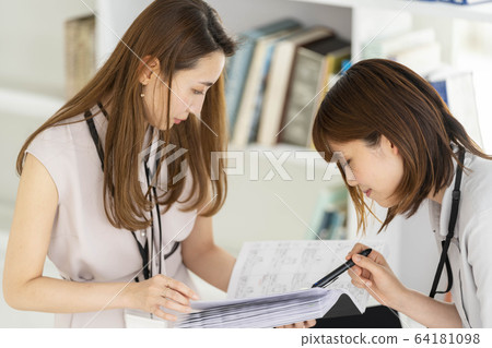 Business scene with two women having a meeting while looking at the drawing 64181098
